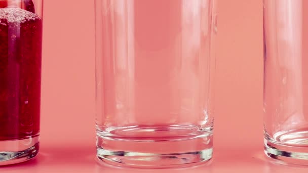 Sok Granatu Wlewa Się Szklanych Pucharów Różowym Tle Zwolniony Ruch — Wideo stockowe