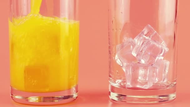 Апельсиновый Сок Наливают Стеклянные Чашки Льдом Розовом Фоне Медленное Движение — стоковое видео