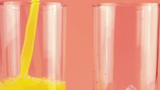 橙汁倒入玻璃杯中 杯中冰封在粉红色的背景上 慢动作 — 图库视频影像
