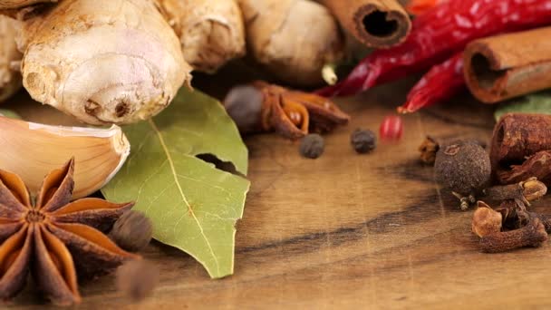 生姜の根 赤唐辛子 スターアニス ベイリーフ ニンニクとクローブの背景に木製のボード上のピーマンの混合物の落下エンドウ豆 — ストック動画