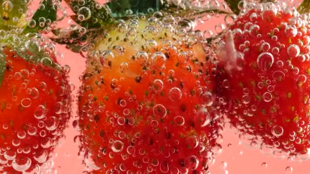 분홍색 배경에 방울에 딸기를 놓는다 — 비디오
