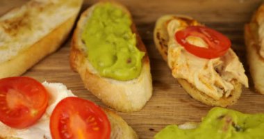Humus, guacamole ve krem peynir üzerine taze domates ve kızarmış ekmek. Tahta kesme tahtasında çeşitli atıştırmalıklar. Vejetaryenler için yiyecek..
