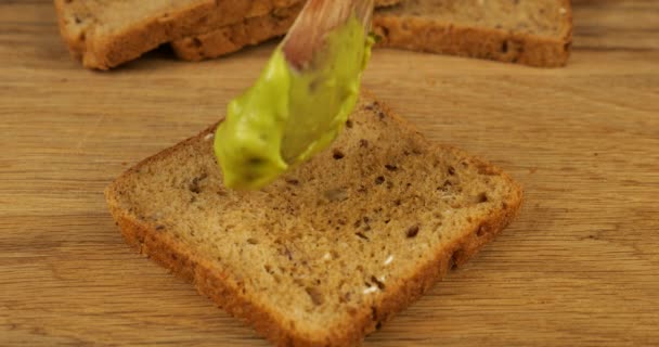 Guacamole Colado Pedaço Pão Multigrãos Uma Placa Corte Madeira Alimentos — Vídeo de Stock