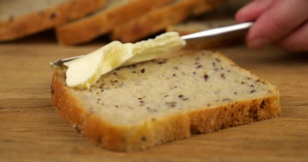 Masło Rozkłada Się Nożem Kawałku Wieloziarnistego Chleba Drewnianej Desce Krojenia — Wideo stockowe
