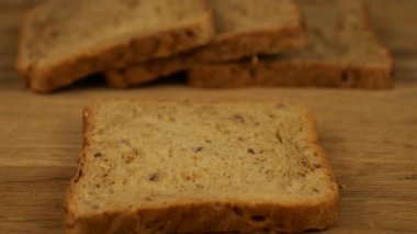 Krem peynir, tahta kesme tahtasındaki çoklu tahıllı ekmeğe bıçak ile sürülmüş..