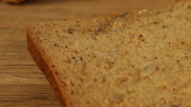 Krem peynir, tahta kesme tahtasındaki çoklu tahıllı ekmeğe bıçak ile sürülmüş..
