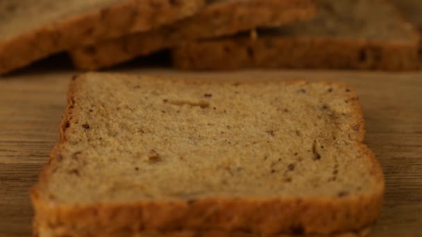 木製のまな板の上に多粒パンの上にナイフで広がるクリームチーズ — ストック動画