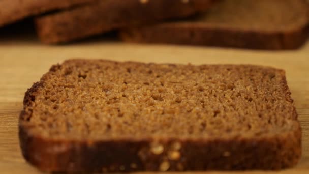 バターは 木製のまな板の上にライ麦パンの部分にナイフで広げられています — ストック動画