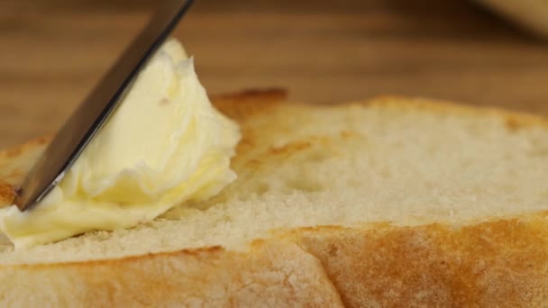 バターは 木製のまな板にトーストした小麦パンの上にナイフで広げられています — ストック動画
