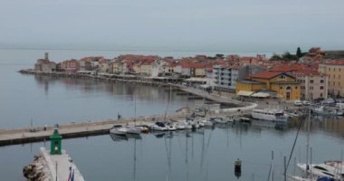 Piran 'ın kırmızı kiremitli çatılarının panoramik hava manzarası, çan kulesi, liman, deniz fenerleri ve tekneler, Adriyatik Denizi akşam ışığında sakin. Slovenya