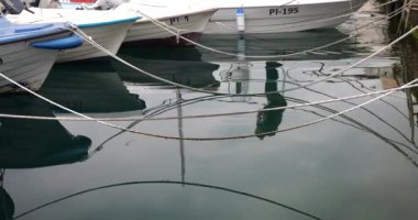 Botların, halatların ve yürüyen bir insanın sularındaki yansıma ve liman