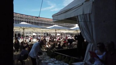 Turistler, Venedik, Piazza San Marco 'daki Procuratie Nuove' da bulunan Florian Kafe 'de dinleniyorlar. 1720 yılında kurulmuş ve İtalya 'da sürekli işletilen en eski ve dünyanın en eski kahvecilerinden biridir..