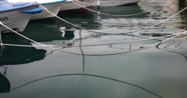 Botların, halatların ve yürüyen bir insanın sularındaki yansıma ve liman