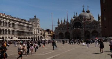 San Marco Meydanı 'nın panoramik manzarası: Procuratie Vecchie, Clocktower, St. Mark Bazilikası' nın batı cephesi, Campanile di San Marco ve İtalya 'nın Venedik kentinde yürüyen turistler.