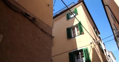 Eski Akdeniz kasabasında geleneksel evler panjurlu pencereler, dar sokaklar ve güneşli bahar sabahlarında mavi gökyüzü. Aşağıdan yukarıya bak.