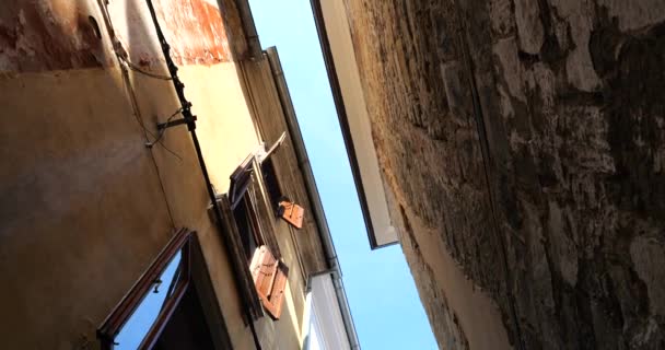 在欧洲一个古老城镇狭窄的街道上的房屋之间 可以看到一条明亮的蓝天的狭长地带 从下往上看 — 图库视频影像