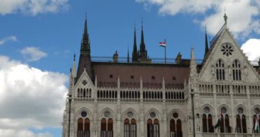 Macar Parlamento Binası neo-gotik tarzda ve rüzgarda dalgalanan Macar bayrakları. Budapeşte, Macaristan.