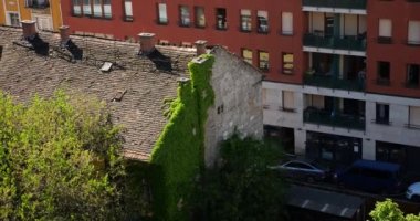 Kırmızı kiremit çatılı eski bir ev sarmaşıkla kaplı bir duvar ve modern bir konut binası. Yukarıdan bak. Budapeşte, Macaristan.