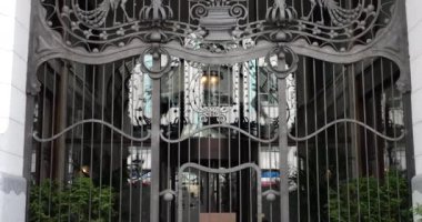 Bitki elementleri ve kuşlarla dekore edilmiş demirden kapıları olan bina..