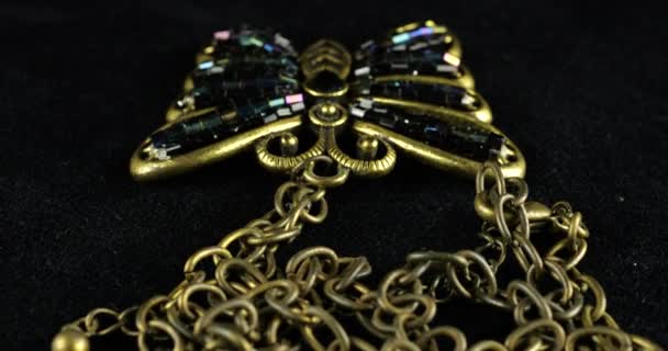 老式的大吊坠 形状为蝴蝶 有青铜色的金属链在纺丝天鹅绒展示盒上 蝴蝶的翅膀装饰着蓝色珠子 — 图库视频影像