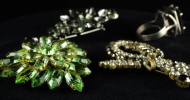 Eski moda bijouterie ve takılarla kadife kaplama vitrin. Kahverengi, beyaz, gri ve yeşil kristalli broşlar ve dumanlı kuvars gümüş yüzük..