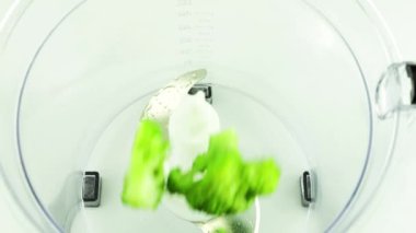 Parlak yeşil brokoli çiçekleri blender kasesine dökülür. Yavaş çekim.