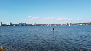 Bir kadın açık bir sonbahar gününde Kanada, Ontario, Barrie 'de bulunan Simcoe gölünde SUP (Stand Up Paddling) sürüyor..