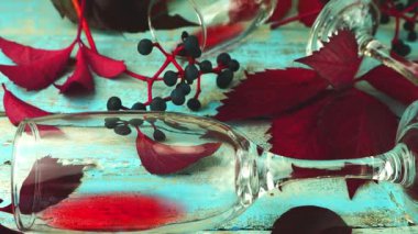 Kırmızı şarap, yapraklar ve düşen üzümlerle dolu mavi bir tahtanın üzerinde sonbahar kompozisyonu. Yavaş çekim.