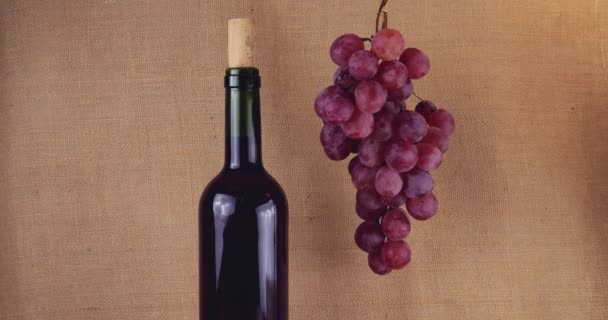 Ροζ Σταφύλια Και Μπουκάλι Κρασί Φόντο Λινάτσα — Αρχείο Βίντεο