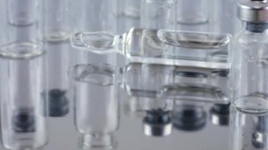 Cam şişelerin ve ampullerin arka planında metal bir yüzeye düşen tabletler ve haplar. Ağır çekim. İlaç ve sağlıklı..