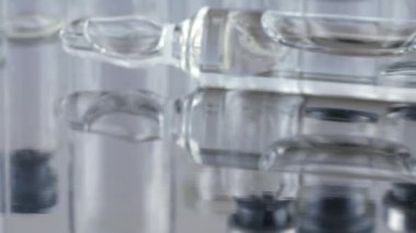 Cam şişelerin ve ampullerin arka planında metal bir yüzeye düşen tabletler ve haplar. Ağır çekim. İlaç ve sağlıklı..