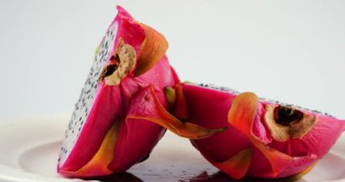 Beyaz arka planda izole edilmiş bir tabakta iki yarım ejderha meyveli pitahaya..