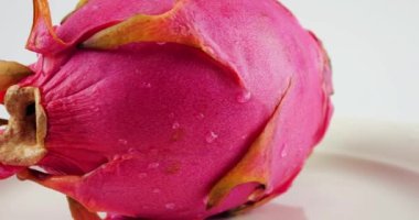 Beyaz arka planda izole edilmiş bir tabakta su damlalarında ejderha meyvesi pitahaya.