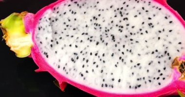 İki yarısı ejderha meyveli pitahaya siyah taşlı servis tahtasının üzerinde..