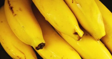 Siyah bir zemin üzerinde bir avuç muz sıçrama ve su damlacıklarıyla.