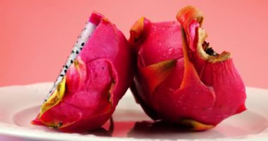 Pembe arka planda izole edilmiş bir tabakta iki yarım ejderha meyvesi Pitahaya..