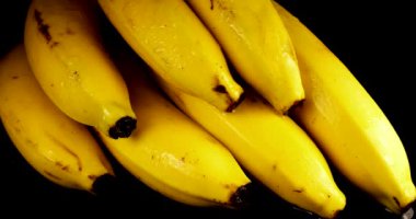 Siyah bir zemin üzerinde bir avuç muz sıçrama ve su damlacıklarıyla.