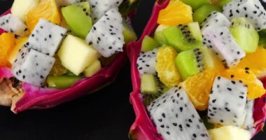 Sağlıklı diyet arınma meyve salatası. Ejderha meyvesinin deri kasesinde servis tahtasında. Bir dilim portakal, kivi, elma..