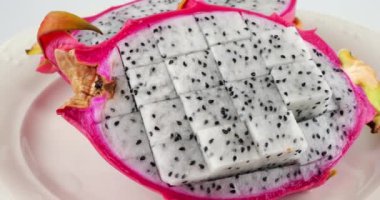 Beyaz arka planda izole edilmiş bir tabakta iki dilim ejderha meyvesi..