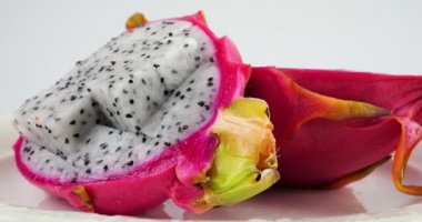 Beyaz arka planda izole edilmiş bir tabakta iki dilim ejderha meyvesi..