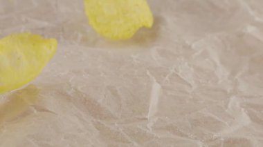 Mutfak parşömeninin üzerine patates cipsi düştü. Yavaş çekim.