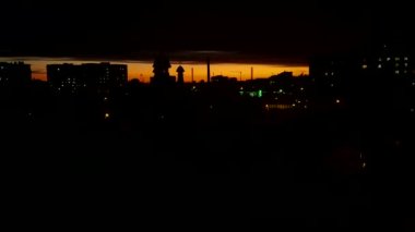 Gece şehrinin binaları günbatımının ve bulutların arka planına karşı.