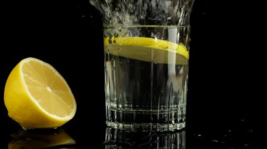 Bir dilim limon bir bardak suya düşer. Yavaş çekim.