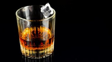 Buz küpleri bir bardak viskinin içine düşüyor. Yavaş çekim.