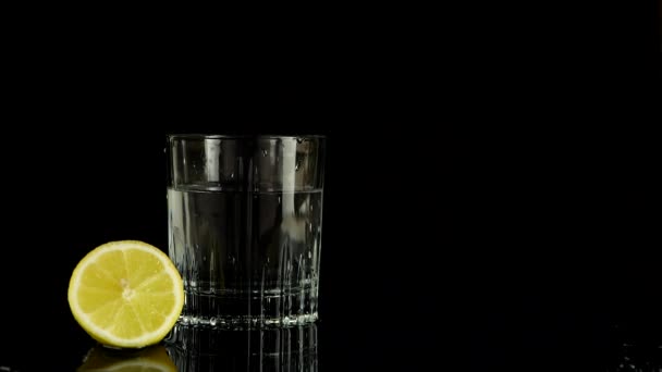 Een Schijfje Citroen Valt Een Glas Water Langzame Beweging Geïsoleerd — Stockvideo