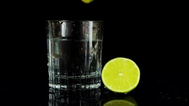 Bir dilim kireç bir bardak suya düşer. Ağır çekim. Siyah arkaplanda izole.