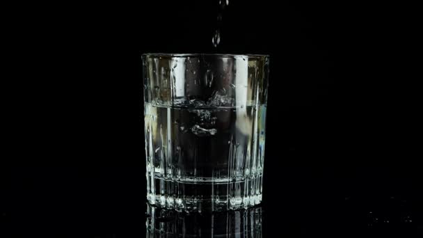 Ijsblokjes Vallen Een Glas Water Een Zwarte Achtergrond Langzame Beweging — Stockvideo
