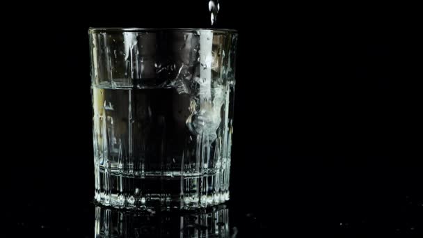 Ijsblokjes Vallen Een Glas Water Een Zwarte Achtergrond Langzame Beweging — Stockvideo