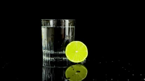 Шматочок Лайма Потрапляє Склянку Води Повільний Рух Ізольовані Чорному Тлі — стокове відео