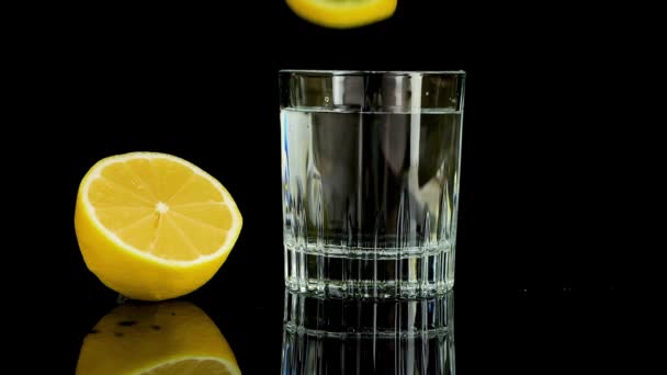 Кусок Лимона Падает Стакан Воды Медленное Движение Изолированный Черном Фоне — стоковое видео